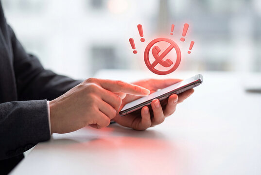 Man blocking unwanted spam or scam calls on a smartphone with a red warning icon
