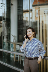 Fototapeta premium Woman talks on phone outside a shop in a city during the daytime