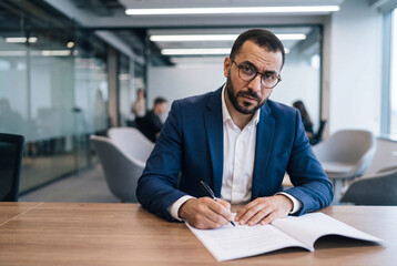 Fototapeta premium Professional middle eastern businessman writing in a notebook at a modern office desk