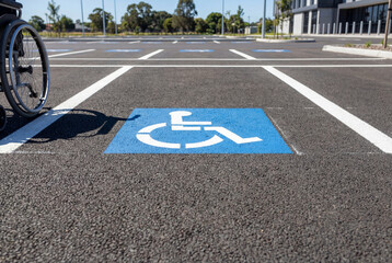 Obraz premium Blue disabled parking symbol painted on asphalt road with wheelchair wheel