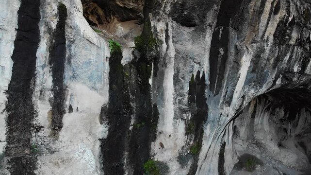 Aerial view moving away from the entrance of an ancient Lycian rock tomb carved into a cliffside, ab01