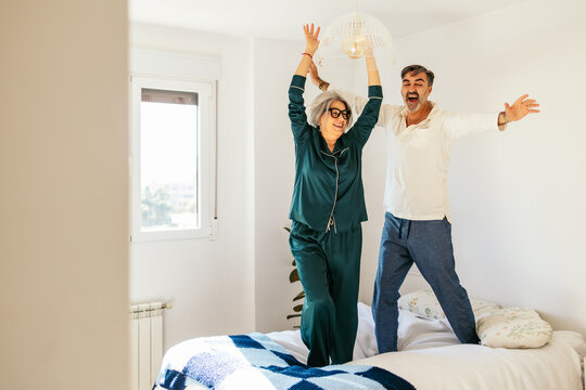 Mature couple having fun jumping on bed together