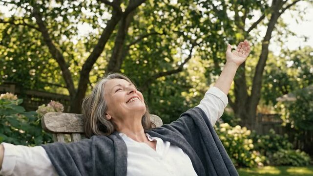 Joyful Senior Woman Relax on Lounge Chair in Garden with Arms Outstretched