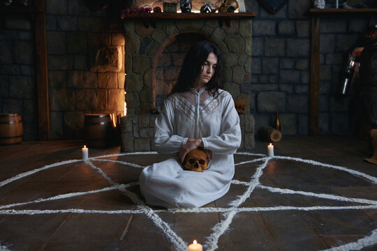 Graceful woman in ceremonial attire practicing reverent rituals amidst candlelit surroundings