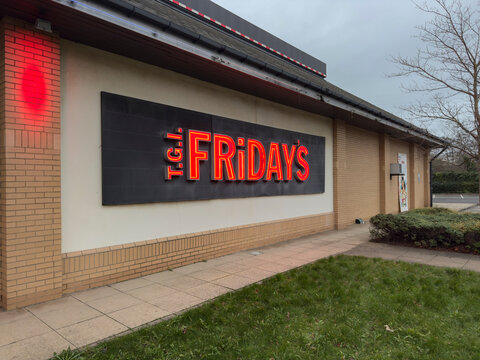 Sheffield, Yorkshire, united kingdom, December 27th 2025 TGI Friday's Neon Sign On Brick Restaurant Exterior With Sidewalk And Overcast Sky