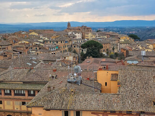 Obraz premium Aerial View of Medieval Rooftops in Siena, Italy. Scenic Cityscape of Tuscan Town with Terracotta Tiles and Historic Architecture. Panoramic Skyline of Siena's Ancient District in Tuscany