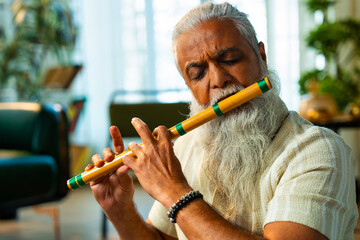 Practicing wooden flute at home, Indian mid age man doing riyaz at modern home © StockImageFactory