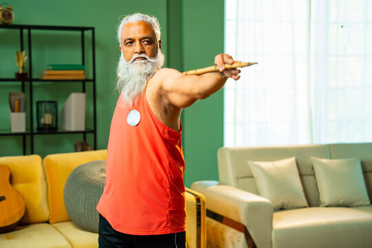 Bearded Indian man performing mobility workout with staff or stick indoors at home