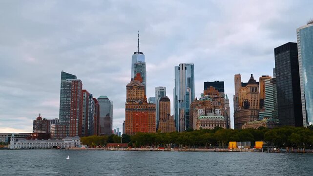 Skyscrapers panorama of Lower Manhattan in New York, USA. The green area and promenade along the shoreline from the riverscape.
