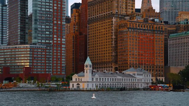 Travelling along the historical white building with a clock tower that served originally as the FDNY Marine Company No.1 Fireboat Station. Approaching Pier A from the riverscape. New York, USA.