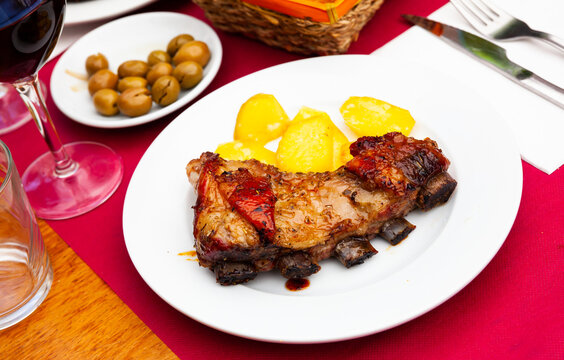 Traditional spanish food Costillar de ternera, beef rack with potato and olives