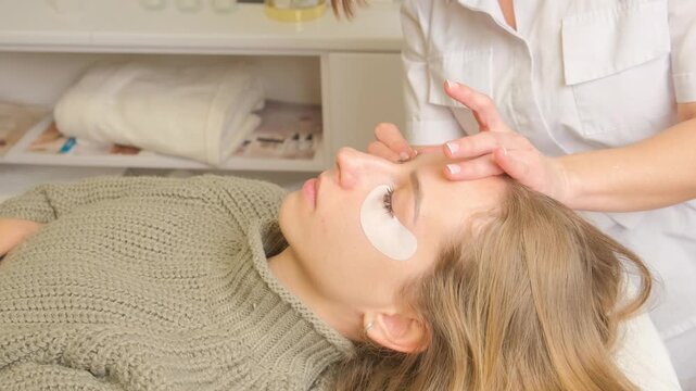 Young woman receiving an eyelash lamination treatment from a professional beautician in a beauty salon