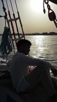 Traveler on Traditional Egyptian Sailboat in Luxor at Sunset Light