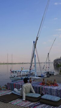 Traveler Relaxing by the Nile River with Felucca Boats in Luxor Egypt