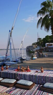Traditional Egyptian Tea Setup by the Nile River with Felucca Boats in Luxor