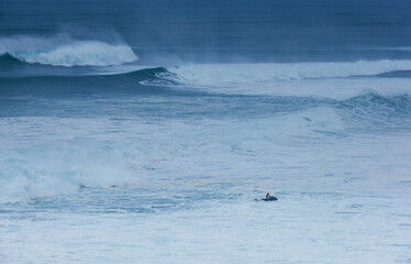 Fototapeta premium Sea doo rider providing safety support for big wave surfers during Nazare huge waves challenge with giant breaking Atlantic ocean swells in Portugal as symbol of extreme water sports and courage