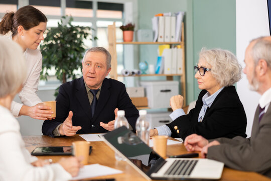Mature business partners or employees of corporation participate at round-table conference, talking and discussing. Staff or co-founder during discussion of companys development strategy