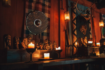 Traditional Viking house interior at Njardarheimr museum in Gudvangen Norway featuring intricate wooden carvings round shield and glowing candles creating warm atmospheric light in historic Nordic roo