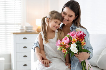 Happy Mother's Day. Mom and her daughter with bouquet of beautiful flowers at home