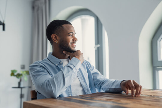 Visualizing success. Head shot of confident stylish young afro american  cheerful man enjoying looking at window thinking happy thoughts. Smiling black hipster guy student businessman imagine future