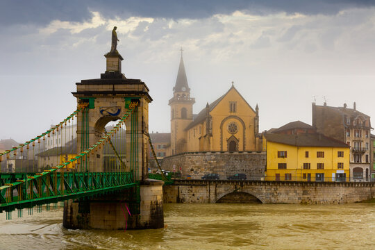 Landscape of the small French commune of Seyssel with the flowing Rhone River and a bridge spanning it