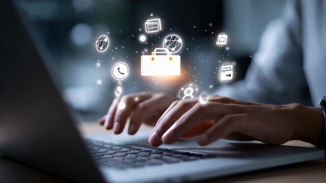 Person typing on laptop with digital icons above in a modern workspace during evening hours