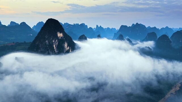 Majestic karst mountain peaks enveloped in thick sea of clouds at sunrise in Guilin, China.