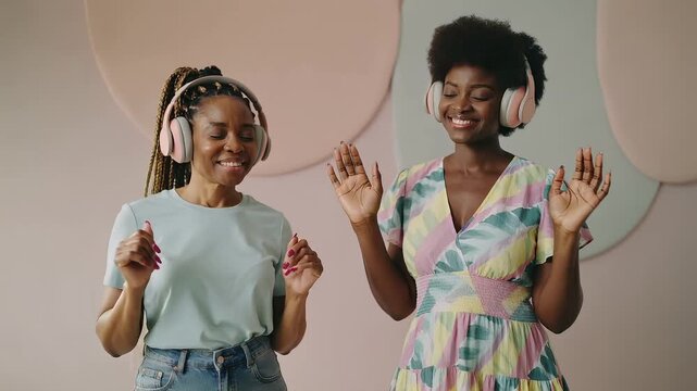Two friends dance and enjoy music while wearing headphones in a bright room at a fun event