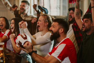 Fototapeta premium Cheering american football fans watching game in bar