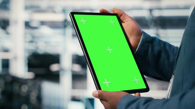 Green screen mockup tablet in server room used by worker to enhance hardware operational effectiveness. Data center engineer using chroma key isolated screen device to monitor gear, camera B close up