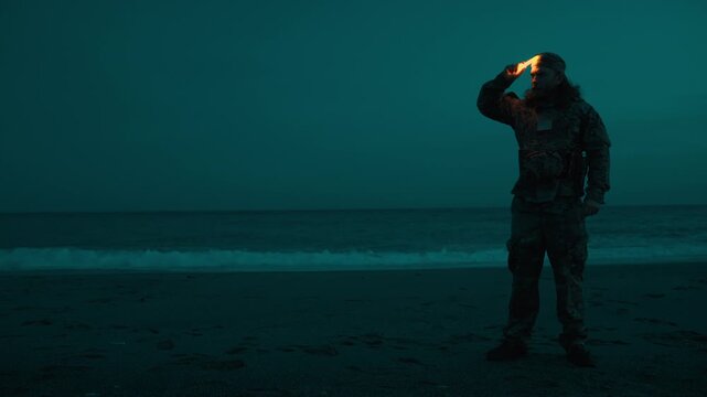 American sailor on a beach near the ocean orienting himself at night