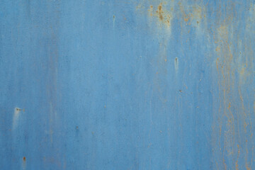 Fototapeta premium A horizontal close-up of a flat blue painted metal surface showing subtle texture, faint scratches, and small spots of orange rust.