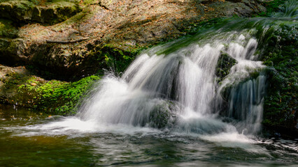 Forest waterfall cascades over mossy rocks. © fotografiecor