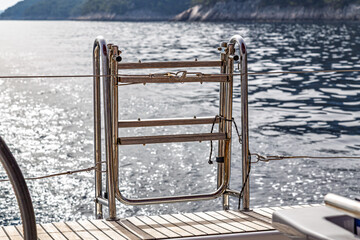 Stainless steel boarding ladder on yacht stern in a close-up view above calm water © Mati