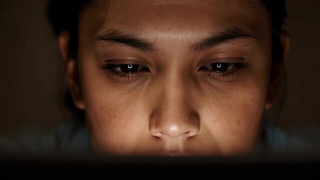Close up person face eyes focused screen young woman concentrated expression soft warm dramatic