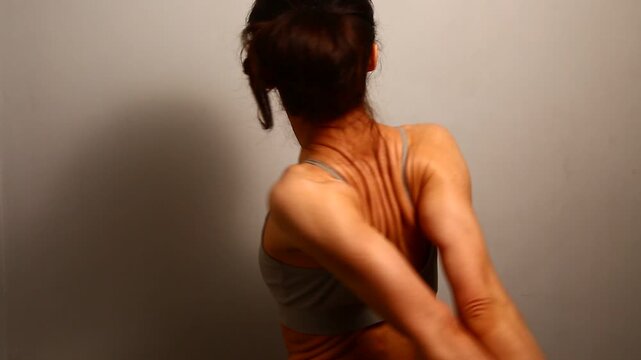 Health sport body woman doing stretching exercises for shoulders, healthy back holding hands clasped in lock behind a back. Fit naked muscles model in bra isolated in studio with copy space. Back view
