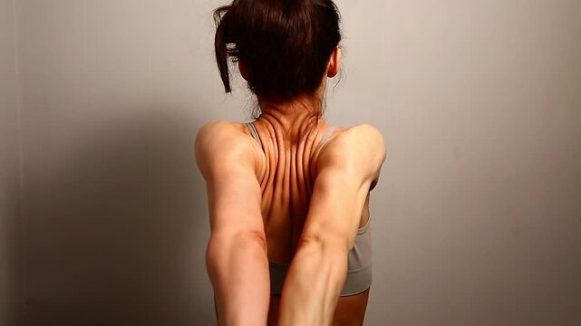 Health sport body woman doing stretching exercises for shoulders, healthy back holding hands clasped in lock behind a back. Fit naked muscles model in bra isolated in studio with copy space. Back view