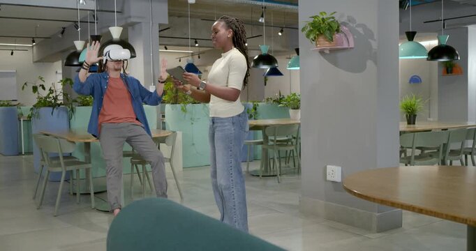 African American duo tapping tablet starting demo, tester wearing VR headset interacting in lounge