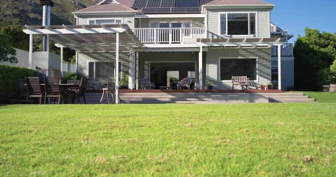 Camera is pulling back to reveal two-story house and rear patio, showcasing solar panels