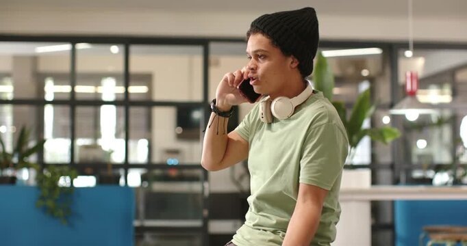 Taking call, African American man speaking on phone, gesturing, clarifying on stool in coworking