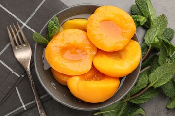 Pickled peaches and mint leaves on grey table, flat lay © New Africa