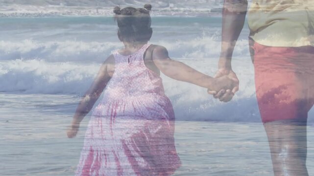 Child in pink dress initiating step, parent holding hand and walking into surf, reaching water edge