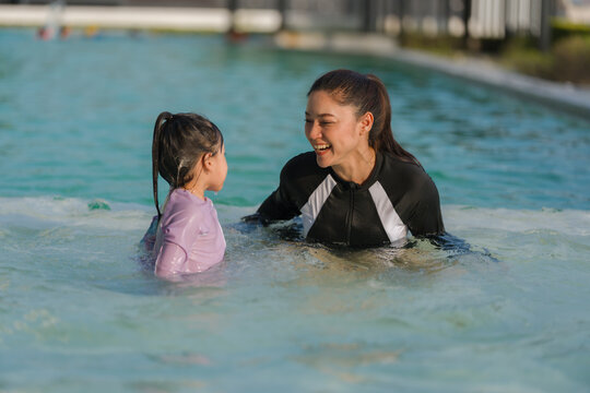 preschool child girl playing and swimming with her mother in pool