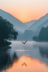 Obraz premium Serene mountain lake at dawn with bird flying over misty water, surrounded by silhouetted hills and trees reflecting golden sunrise colors in calm surface.