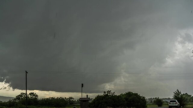 Dark shelf cloud of a severe thunderstorm rolling in over trees before hail and rain hit, Montana, time lapse