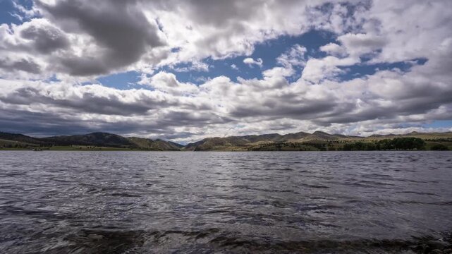 Slider shot of puffy clouds moving over wind-rippled water and hills at Gates of the Mountains on the Missouri River, Montana, time lapse