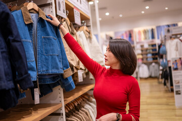 Woman shopping choosing denim jacket in clothing store