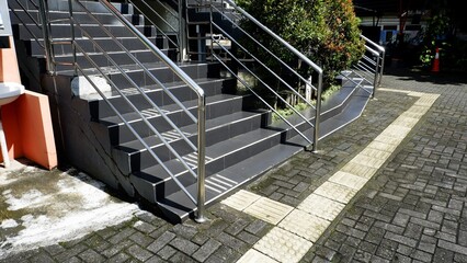 This high-angle shot captures the clean lines of an institutional building. The reflective metal handrails and polished floors lead the eye toward bookshelves and desks in a quiet study area. © agung