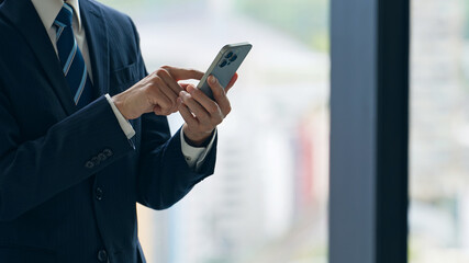 オフィスでスマホを使うビジネスパーソン © metamorworks