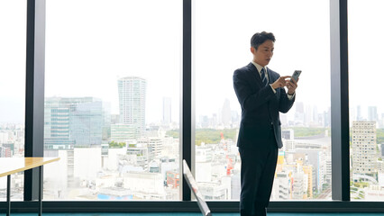 ロビーでスマホを見る男性ビジネスパーソン © metamorworks